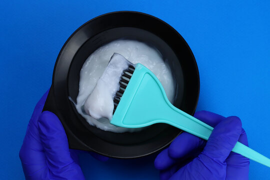 barber mixes the hair dye with a brush in a bowl