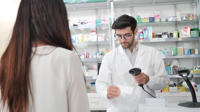 Middle eastern male pharmacist scanning barcode of medicine drug to customers in modern pharmacy. Slow Motion