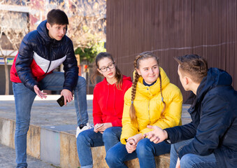 Fototapeta premium Group of modern teenagers hanging out on streets of city on warm spring day..