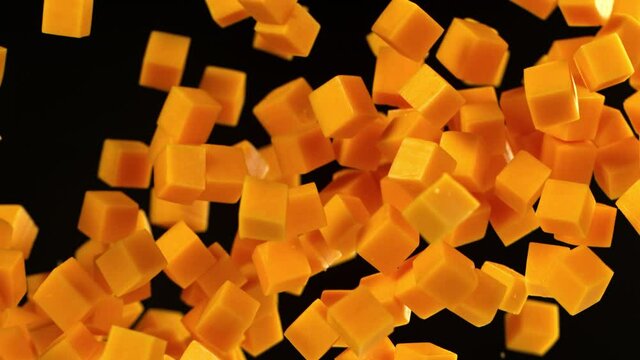 Super Slow Motion Shot of Flying Cheddar Cheese Cubes on Black Background at 1000 fps.