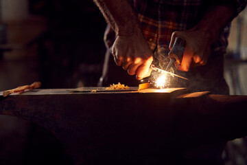 Close Up Of Male Blacksmith Lighting Wood Shavings With Firesteel On Anvil To Light Forge