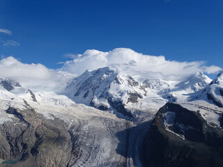 Glacier flowing down between snow-capped peaks and view of the highest mountain in the german-speaking alps, the Dufourspitze