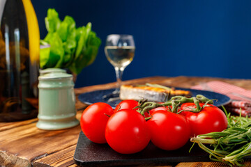 Cherry tomatoes and herbs on wooden table with bottle of wine