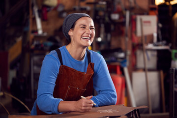 Female Blacksmith Wearing Headscarf Working On Design In Forge