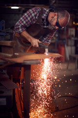 Male Blacksmith Using Plasma Cutter To Cut Shape From Sheet Metal In Forge