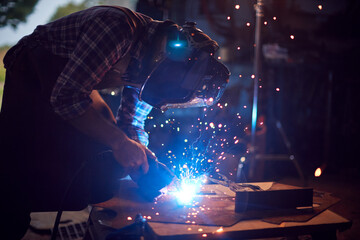 Male Blacksmith Wearing Protective Safety Visor Arc Welding Metalwork In Forge