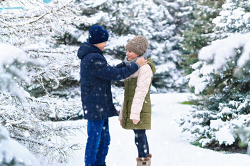 teens portrait in a winter forest, boy and girl, beautiful nature with bright snowy fir trees