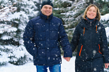 couple walking in a winter forest, two adult people, man and woman, beautiful nature with bright snowy fir trees