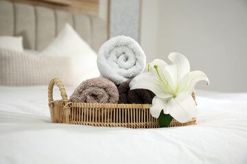 Rolled clean towels and flower on bed indoors