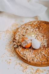 Three easter eggs on wooden background with sawdust around. Happy Easter card. Easter eggs with lace border, wooden cutting board on white table. Eggs decoration. Golden easter egg.