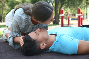 Young woman checking for breathing of unconscious man outdoors