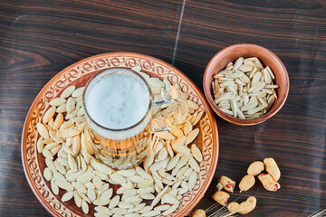 Sunflower seeds, peanuts and a glass of beer on wooden table