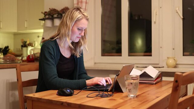 Junge Frau arbeitet abends zuhause im Homeoffice am Laptop