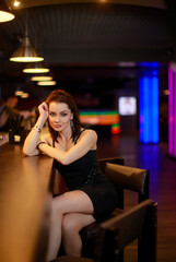 Plakat Beautiful brunette woman in evening dress posing near bar alone