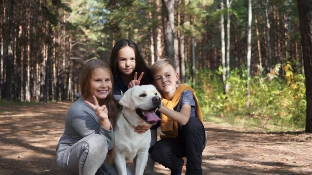 Children try to take a picture with a dog who is running away