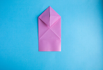 Step-by-step instructions for creating  origami bunny out of colored paper on  blue background, for  decorative Easter party decoration or for small Easter gifts.