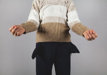 Boy shows her empty pockets. Gray background.