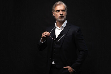 Portrait of a respectable mature man in a suit and sunglasses on a black background. Businessman...