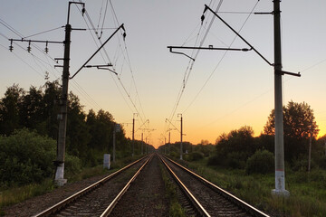 Fototapeta na wymiar Railway rails go off into the distance at sunset in summer