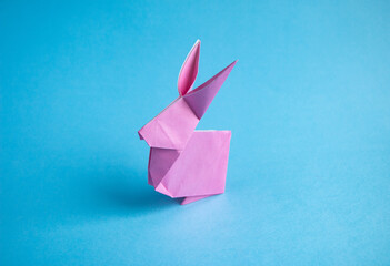 Step-by-step instructions for creating  origami bunny out of colored paper on  blue background, for...
