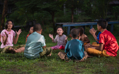 Obraz premium Group of Asian children in traditional costumes playing outdoor activities. local traditional game in Thai culture concept. 