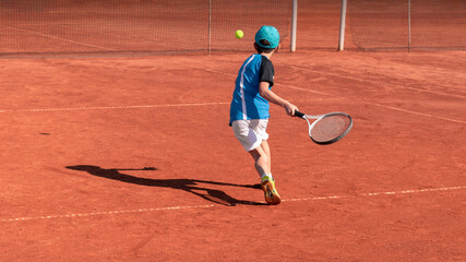 Child on tennis court. Boy tennis player learning to hit forehand . Physical activity and sports...