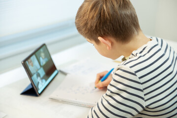 Teenager schoolboy at virtual lesson at home using tablet during homeschooling at pandemic quarantine