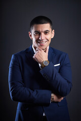 Portrait of a businessman in blue jacket on dark background in studio. man with short haircut. Young confident manager smiles