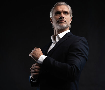 Handsome middle-aged man in suit posing against black background