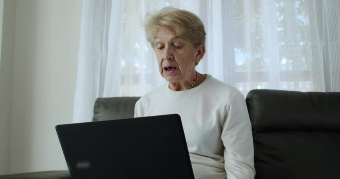 Older women have to work from home with online training meetings and she was in a comfortable position leaning on the sofa at her home alone.