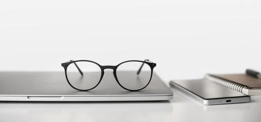 Workplace - laptop computer, smartphone and eyeglasses at office desk table panoramic banner....