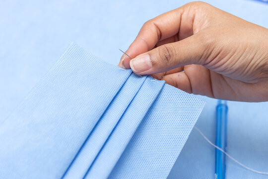 Sewing of protective masks against dirt, smog and virus, close-up view. Home production of face masks from sterilization paper.