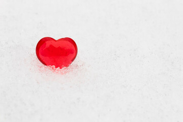 Little red heart in the snow (valentine's day greeting card, selective focus)