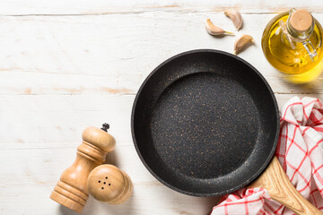 Frying pan or skillet with sea salt and pepper on white wooden table. Top view with copy space.