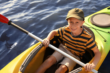 Fototapeta premium Happy little boy kayaking on river, above view. Summer camp activity
