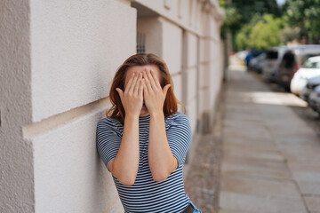 young woman hides her face behind her hands