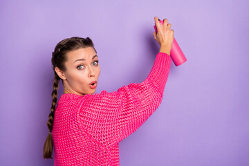 Photo of young amazed shocked surprised girl painting graffiti in pink knitted sweater isolated on violet color background