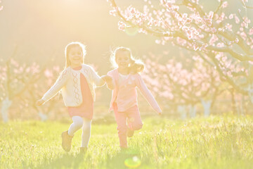 Children outdoors in sunlight. Children run holding hands in the park. High quality photo.