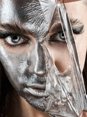 the girl removes a silver-colored cosmetic mask from her face - 408525244