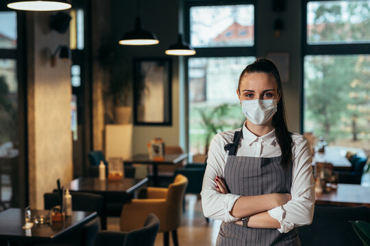 Waitress Standing Arms Crossed In Restaurant, Posing With Protective Face Mask, Covid-19 Concept