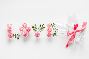 Word Love made of pink flowers and green leaves, overhead view