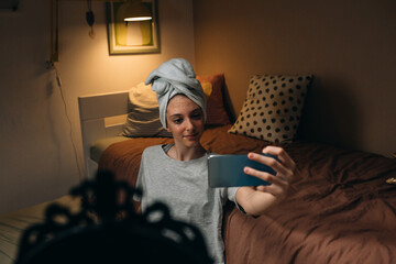 girl applying cosmetic face mask, taking picture with mobile phone