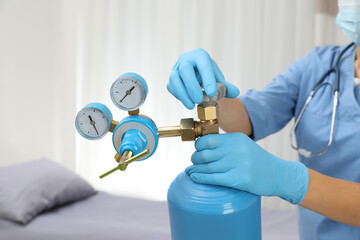 Medical worker checking oxygen tank in hospital room, closeup