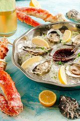 Closeup on a metallic bowl with fresh oysters with ice and lemon