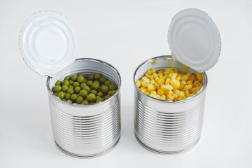 Two open cans with corn and peas on a white background. Copy, empty space for text