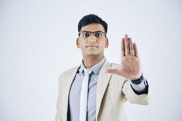 Portrait of young Indian businessman in suit making stop gesture with hand and looking at camera