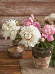 Obraz na płótnie Canvas Still life with white and pink peonies in a old ceramic vase on wooden background