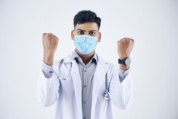 Excited young Indian doctor in protective mask making pump gesture, isolated on white
