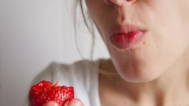 extreme closeup beautiful young woman provocative and appetizing eating strawberry.