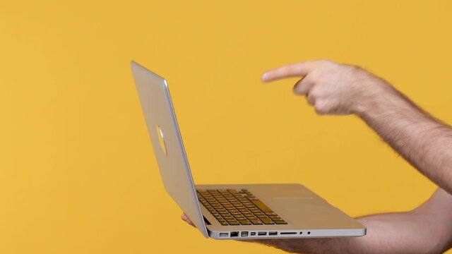 Cropped close up man male hand holding working on laptop pc computer typing on keyboard isolated on yellow background studio. Copy space commercial promo advertisement. Advertising workspace mock up